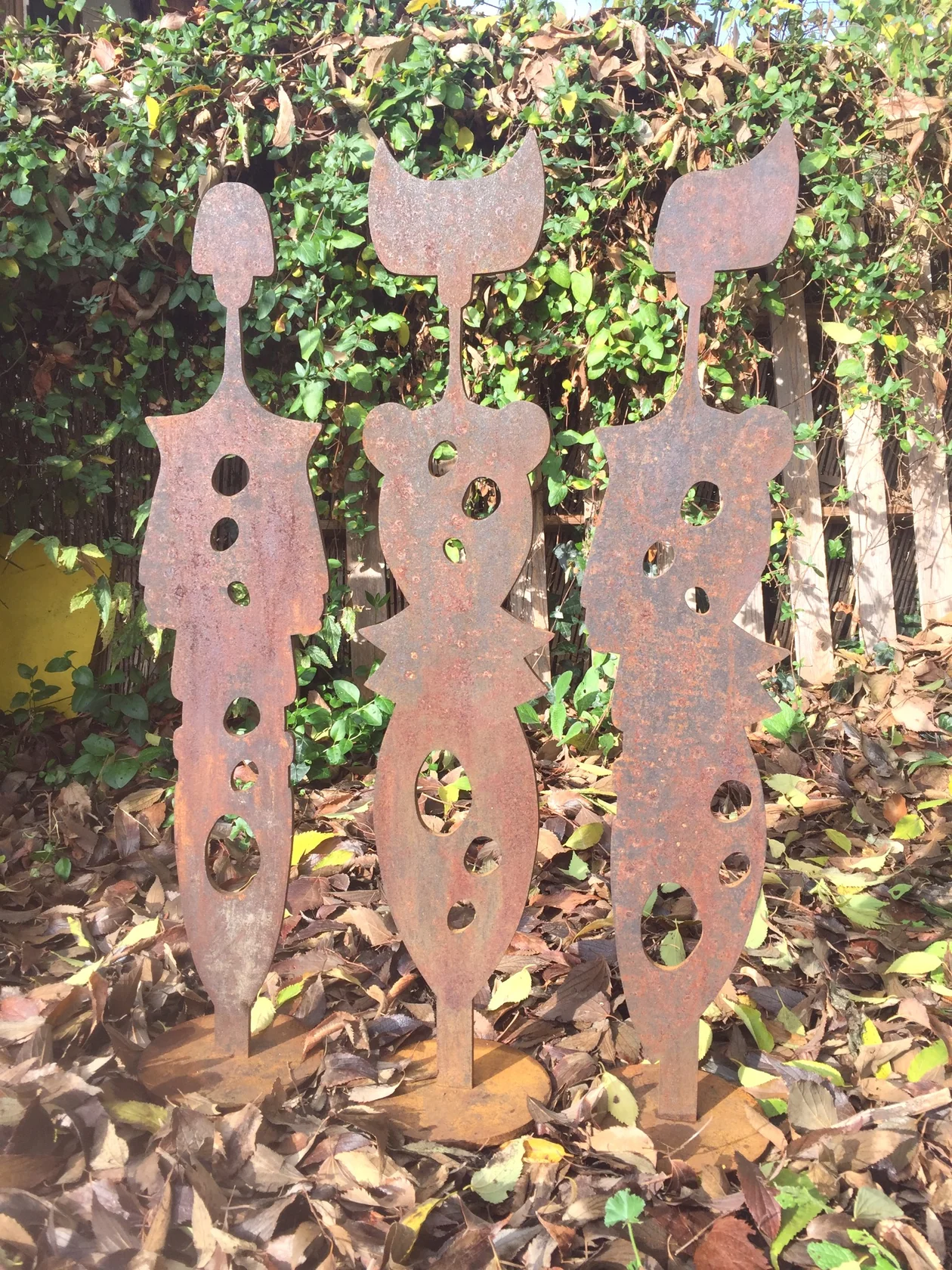 Trois sculptures originales en métal rouillé photographiées dans le jardin